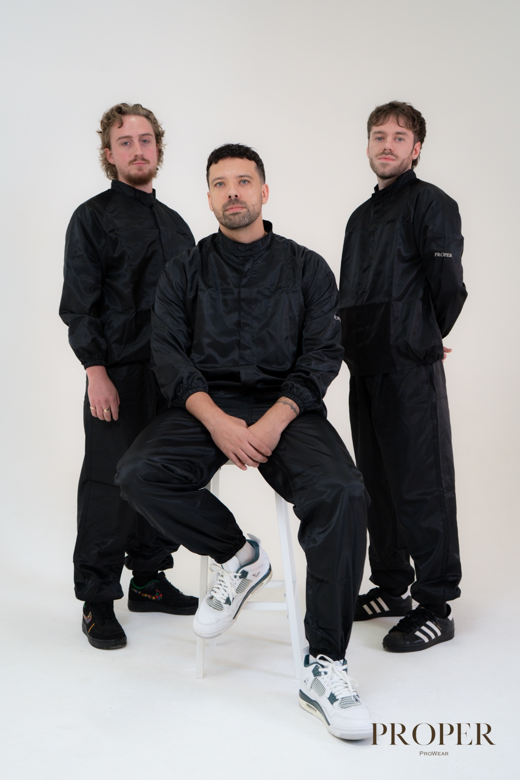 Three barbers wearing black Barber Armour hair-resistant two-piece workwear suits