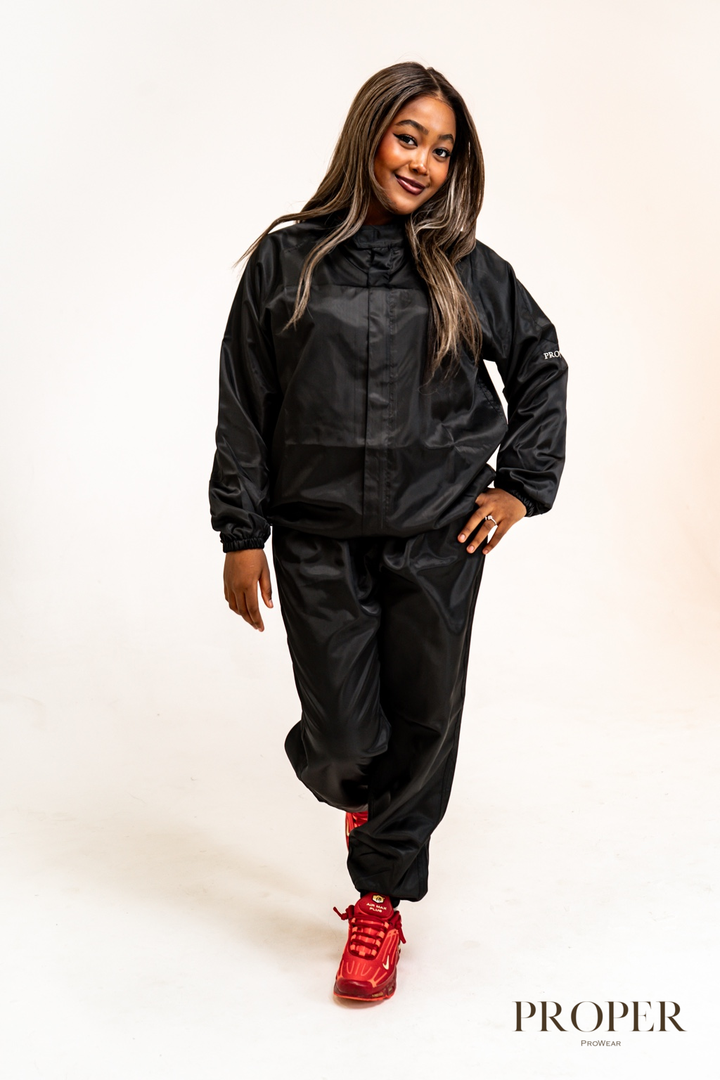Hairdresser wearing the black Barber Armour hair-resistant zip-up jacket and trousers