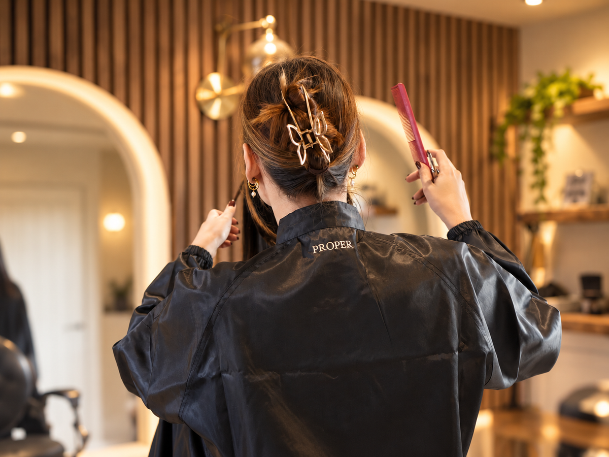 Hairdresser in a salon wearing the black Barber Armour hair-resistant jacket, back view